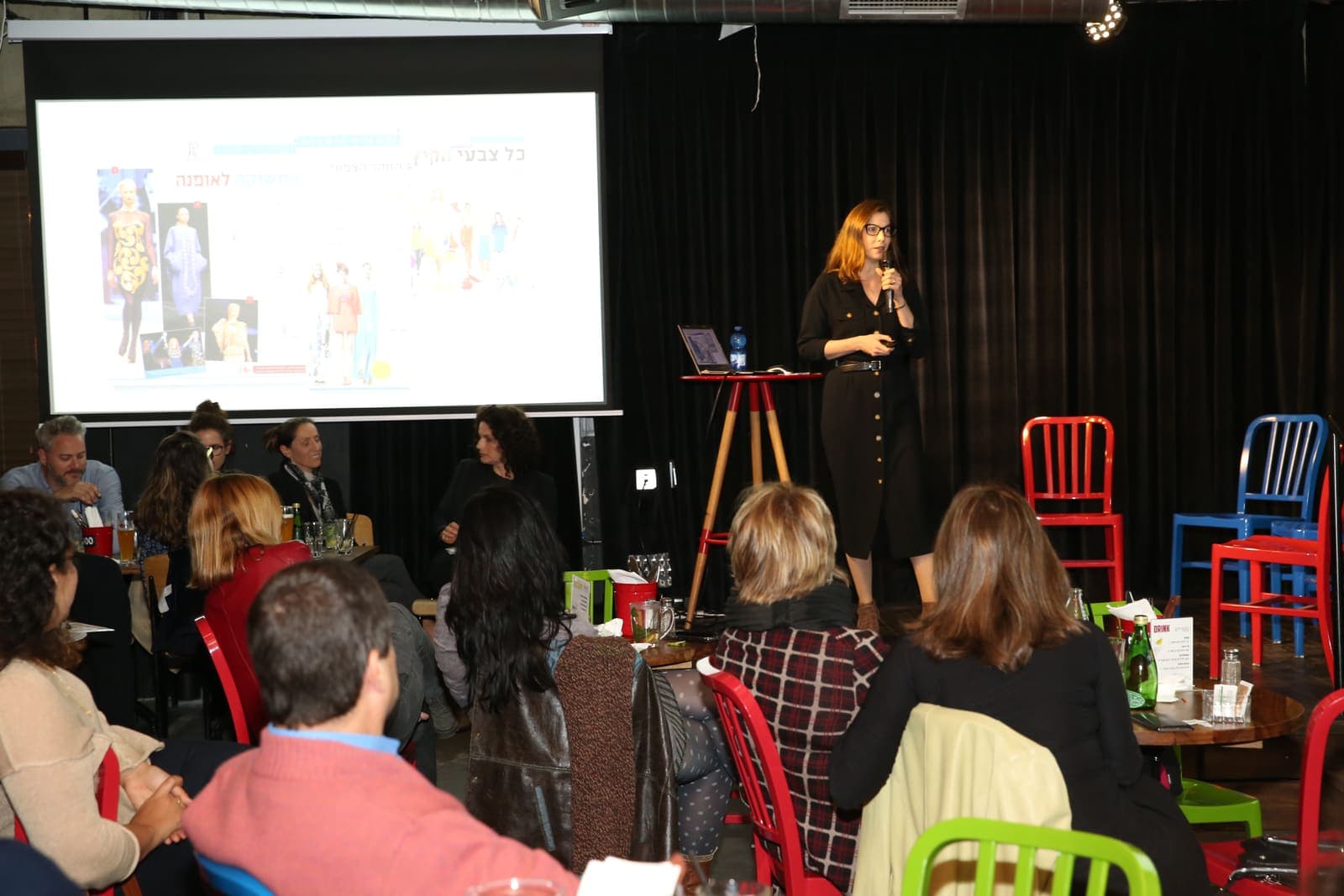 Michal Levi Arbel lecturing to a full room, with slides behind her